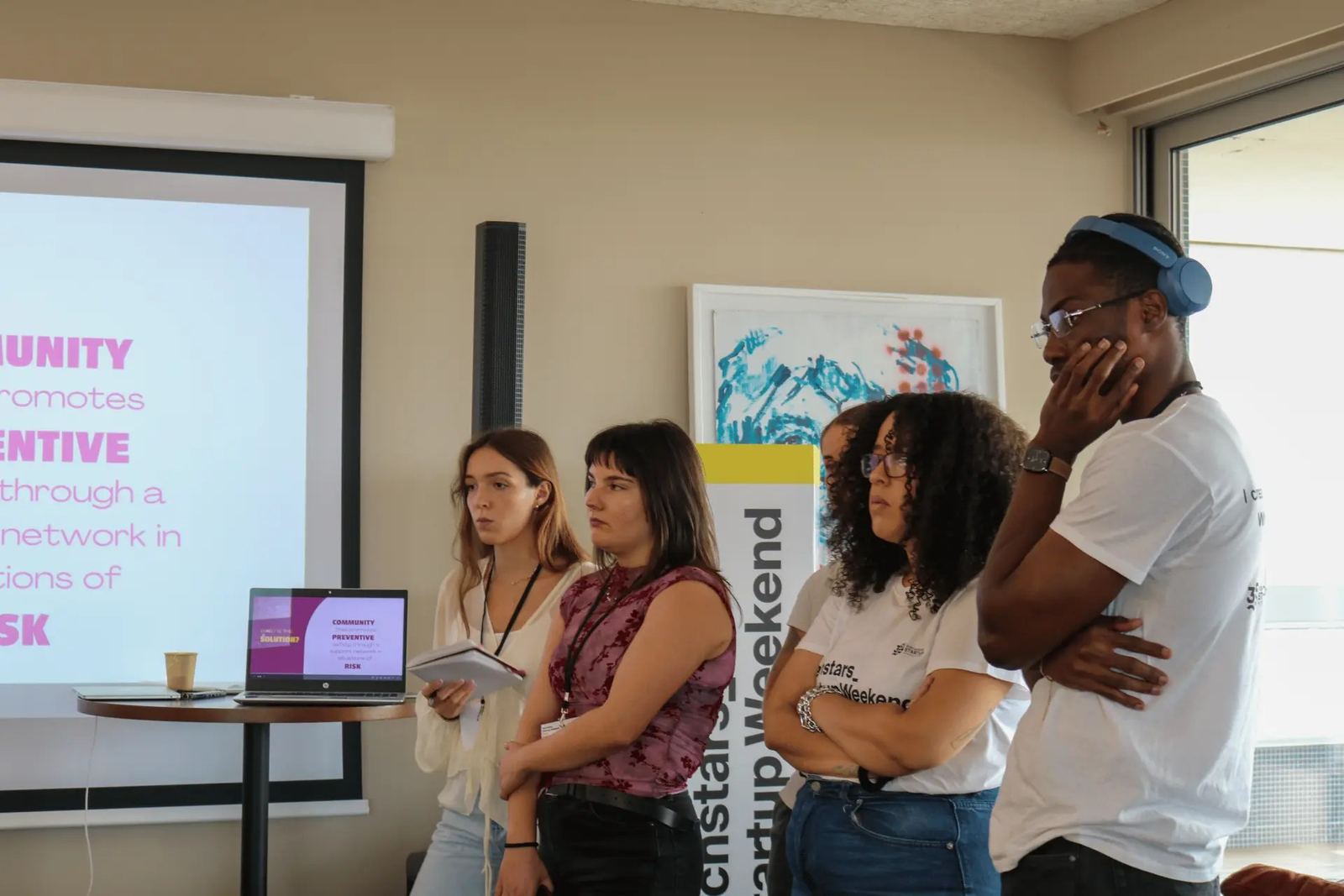 Elio Fernandes (Mvuemba Fernando Bemvindo) and the BetweenUs team by the presentation screen